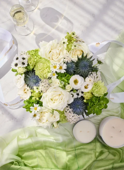 Flower box with white roses, green carnations, daisies, and eryngium