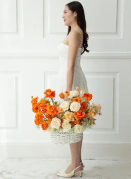 กระเช้าดอกไม้สีส้มขาวถือโดยนางแบบ