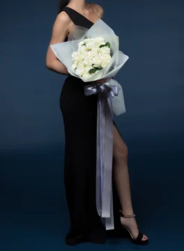 A bouquet of 24 white roses wrapped in blue paper