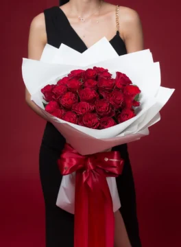 A bouquet of 24 red roses wrapped in white paper