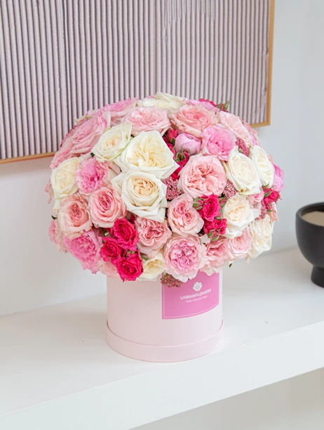 กล่องดอกกุหลาบสีชมพูและขาว จัดอย่างประณีตในกล่องทรงกลมสีชมพูพาสเทล