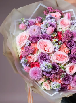 A beautiful bouquet of tulips and purple roses wrapped in a bouquet.