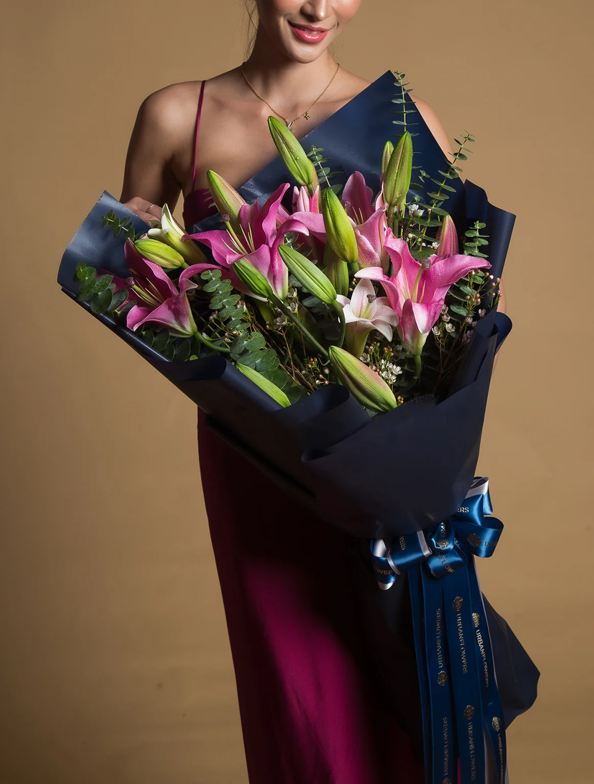 Elegant bouquet of pink lilies and buds, wrapped in deep navy paper with luxury ribbon — a radiant gift that symbolizes admiration and joy.