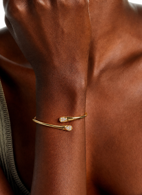 Gold vermeil open bypass cuff bracelet with pavé crystal teardrop tips, worn on wrist.